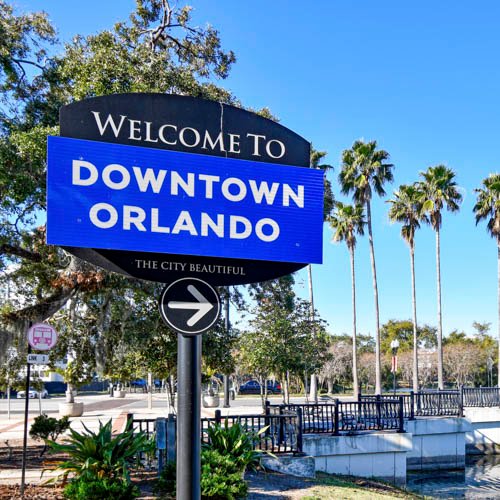 Welcome to Downtown Orlando sign with palm trees and clear blue sky, representing the eco-friendly environment of The Green Bucket's commercial cleaning services in Orlando, FL.